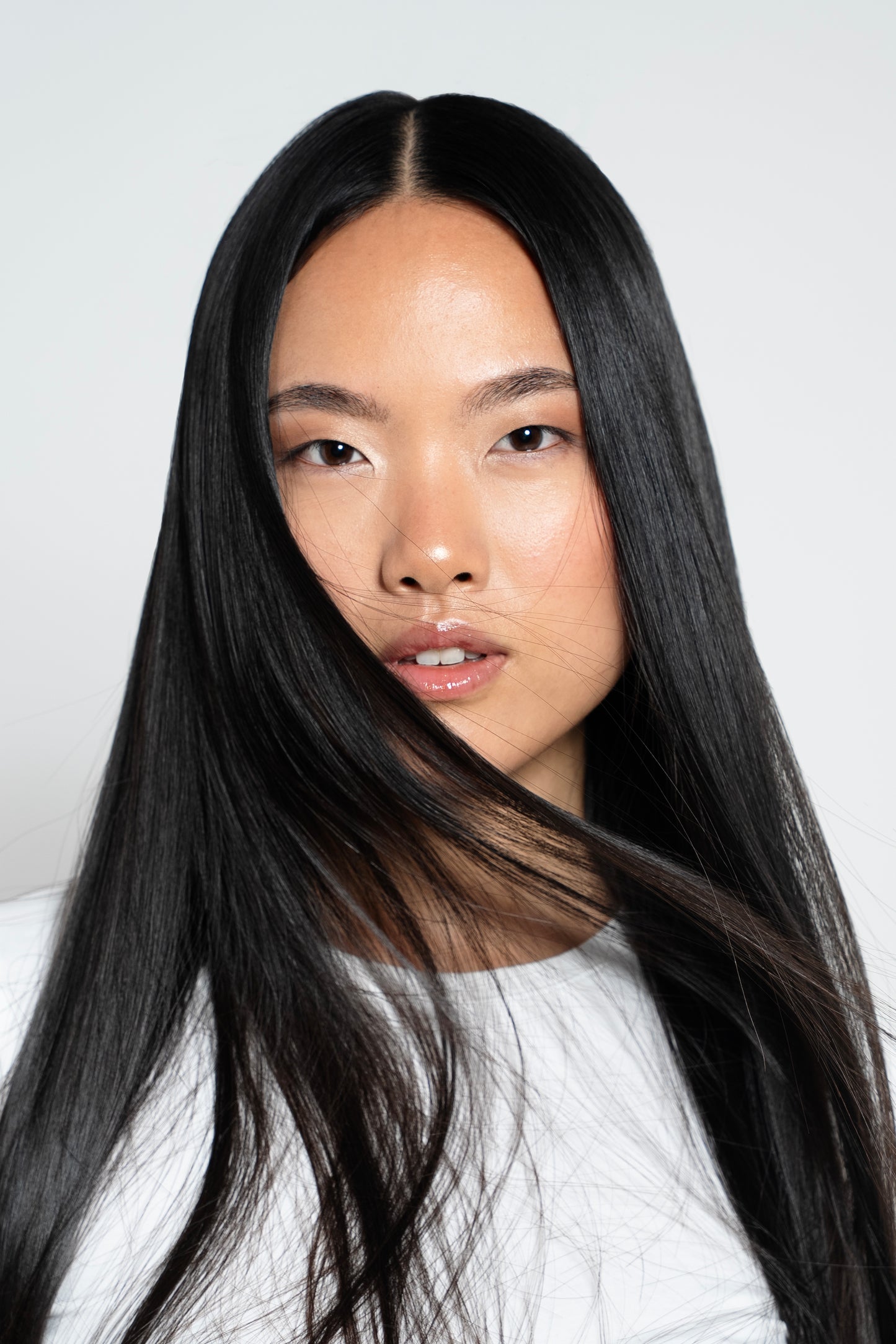 Model wearing deep noir black clip-in hair extensions styled into soft waves