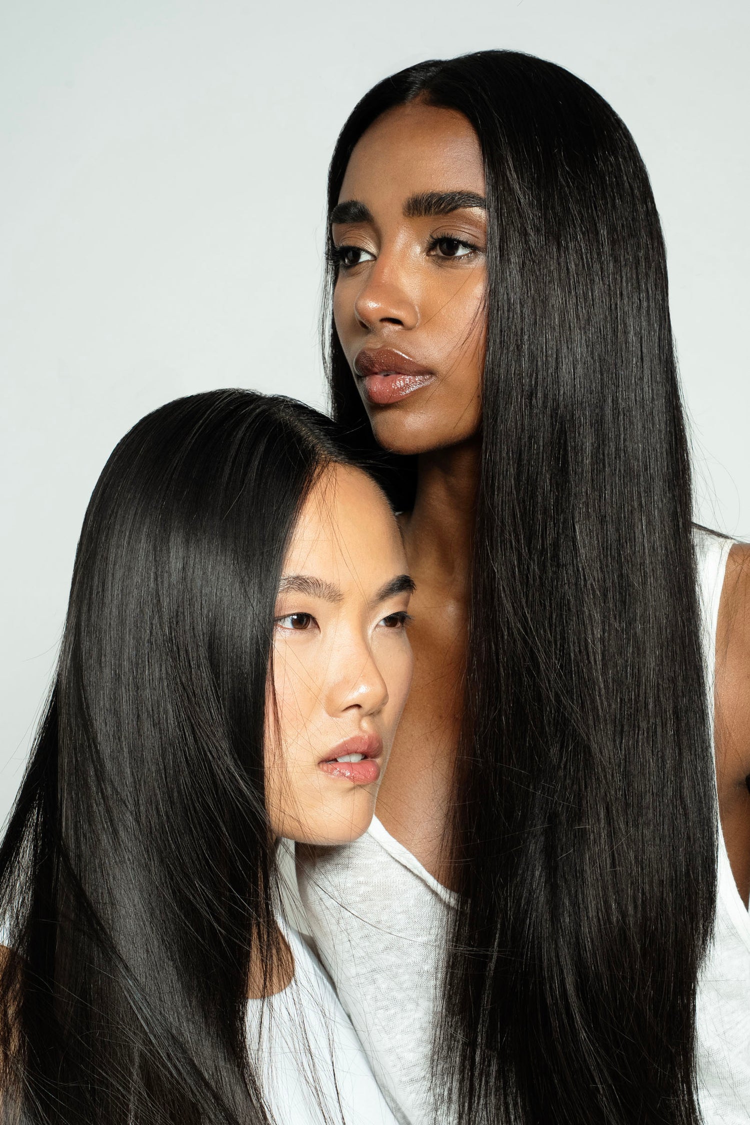 Two women with long, straight black hair against a white background