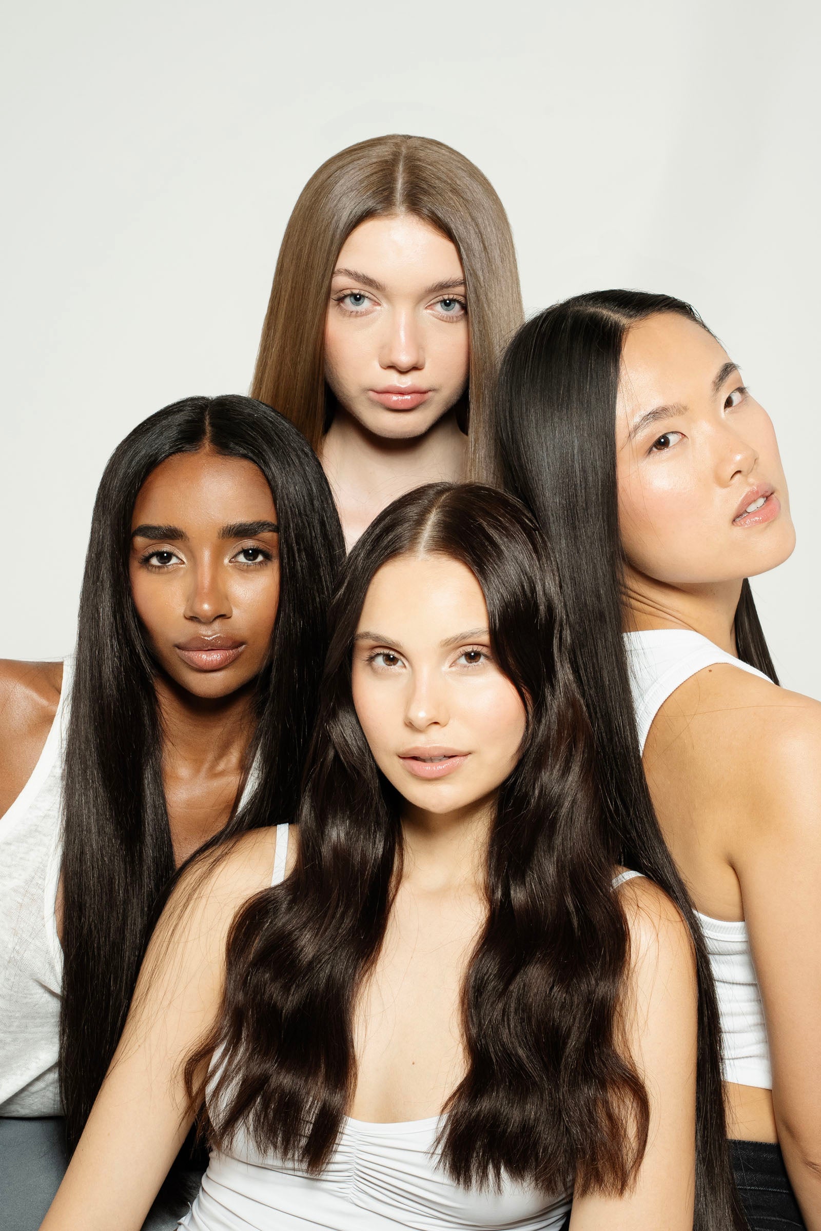 Four women with long, straight hair posing against a white background