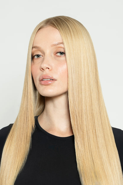 Model styled with neutral blonde clip-ins for a soft, natural-looking finish