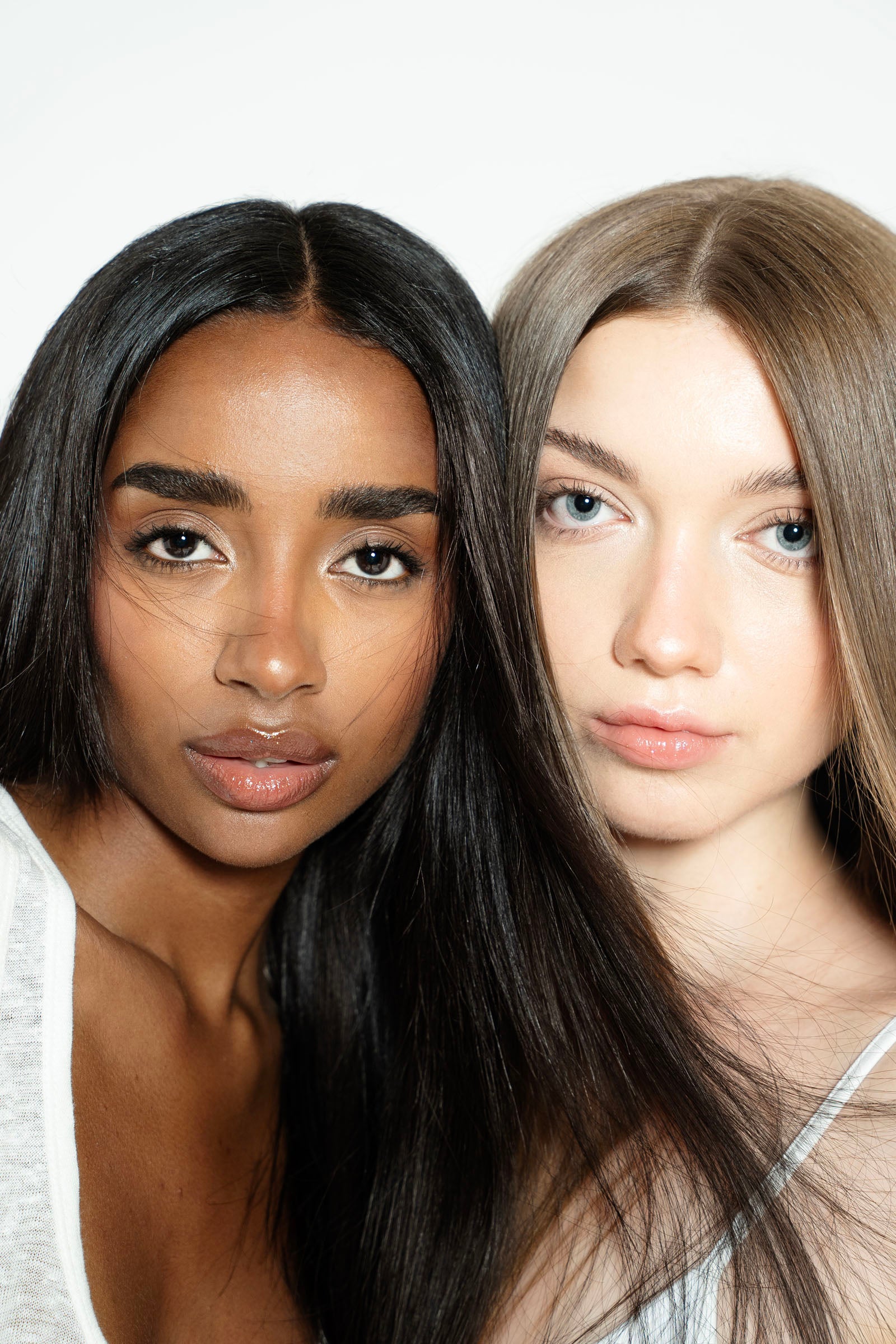 Two women with different hair colors posing against a white background for 1010 Extensions