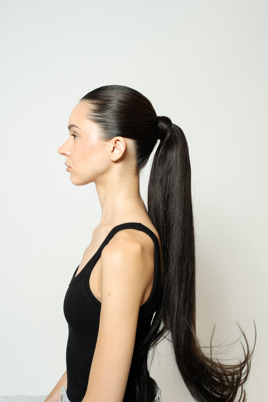 Model with dramatic noir black ponytail extension styled high for a bold, sleek look
